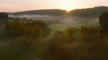 Lüksemburg 'daki sonbahar renkli ormanların ve vadilerin üzerinde sabah sisiyle kaplı hava aracı Sunrise View. 4k drone görüntüsü