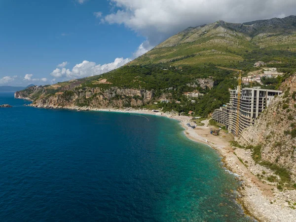 Karadağ 'ın Adriyatik kıyısında bir mimari marifet olan betondan yapılmış otel inşaatı. Perazica Do plajının yakınında vinçleri olan bir bina. Deniz kıyısındaki inşaat alanında.
