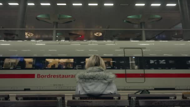 ベルリン中央駅から近代的な新しいインターシティIce高速列車の前にプラットフォームに座っているブロンドガール 高品質の4K映像 — ストック動画