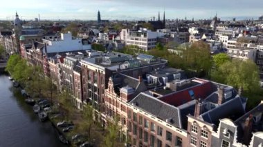 Hollanda, Amsterdam 'ın Tarihi Merkezi. Dar sokaktaki ve kanaldaki geleneksel Hollanda evlerinin insansız hava aracı görüntüleri. 4k UHD, 5k video