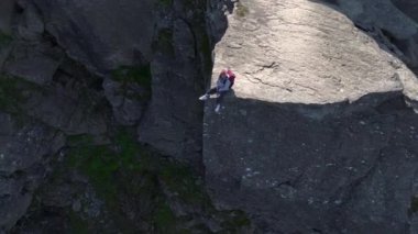 Maceracı Kız Norveç, Trolltunga 'da uçurumun kenarında oturuyor. Hava, Dünya Seyahat Işığı - Trol Dili. Yüksek kalite 4k görüntü
