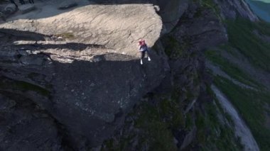 Norveç, Trolltunga 'da uçurumun kenarında bir kız. Norveçli Seyahat Uzmanı Gezgin Gezgin Gezgin Trol Dili 'nde Hava Aracı Atışı. Yüksek kalite 4k görüntü