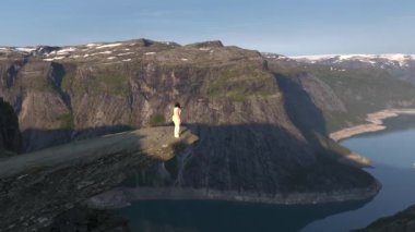 Norveç, Trolltunga 'da uçurumun kenarında bir kız. Norveçli Seyahat Uzmanı Gezgin Gezgin Gezgin Trol Dili 'nde Hava Aracı Atışı. Yüksek kalite 4k görüntü