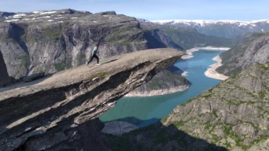 Norveç, Trolltunga 'da uçurumun kenarında bir kız. Norveçli Seyahat Uzmanı Gezgin Gezgin Gezgin Trol Dili 'nde Hava Aracı Atışı. Yüksek kalite 4k görüntü