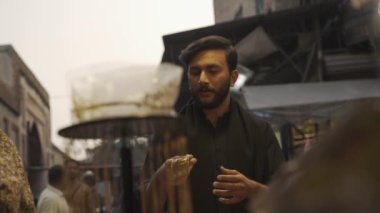 Pakistan 'ın Lahor Duvarlı Kenti' ndeki Sokak Pazarı 'nda yakışıklı Pakistanlı adam indirimi. Müslümanlar geleneksel olarak giyinir. Yüksek kalite 4k görüntü