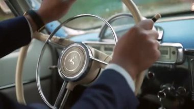 Eski model Volga Gaz 21 kullanan takım elbiseli bir adamın elleri. Sovyet arabasının klasik direksiyonu yüksek kaliteli 4K görüntü.