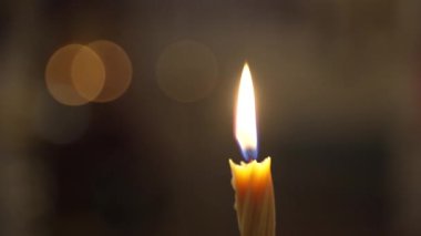 Tek bir beyaz mum yanıyor. İzole edilmiş mum ağır çekimde, koyu arka planda yanıyor. Siyah arka planda sarı gözlüklü beyaz parafin mum yanığı. Ağır çekim. Yüksek kalite 4k görüntü