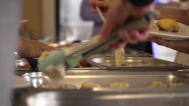 İnsanlar Yemek Servisi Masası 'nda çeşitli yemekler yiyip, yemekleri ısıtıyorlar. Akşam Yemeği Partisinde Çeşitli Yemekler. Yüksek kalite 4k görüntü