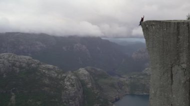 Maceracı Adam Norveç Dağları 'ndaki Pierkestolen uçurumunun kenarında oturuyor. Minber Rock, Norveç. Yüksek kalite 4k görüntü