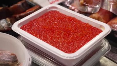 Kırmızı havyarlı büyük plastik bir konteynırın yakın çekimi siyah eldivenli kadınlar tarafından alınır. Bir süpermarket vitrini. Yüksek kalite 4k görüntü