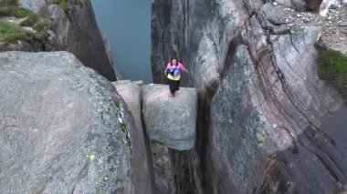 Kız Adventurist Norveç 'te Kjeragbolten' e atlıyor. Fjord Dağları 'ndaki Kjerag Kayası Hava Manzarası. 4k UHD