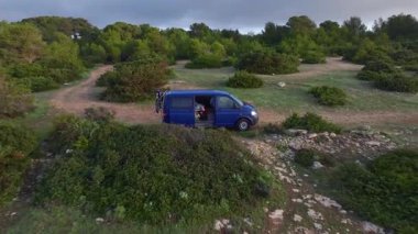 Kamp 'taki adam Portekiz' de okyanusun önündeki bir uçuruma park etti. Hava görüntüsü. Kamp Van Seyahat. Van Life Konsepti. Yüksek kalite 4k görüntü