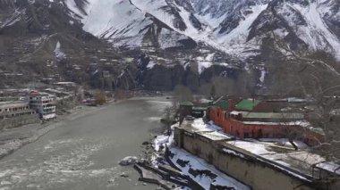 Pakistan 'ın Chitral kentindeki tarihi bir kalenin kışın havadan görünüşü. Kalash Vadisi 'ndeki nehir kıyısında parlak bir bina. Yüksek kalite 4k görüntü