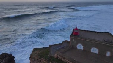 Nazare Deniz Feneri. Portekiz 'deki en büyük dalgalar. Büyük Naziler Dalgaları, Günbatımı Zamanı Hava Aracı Atışı. Yüksek kalite 4k görüntü