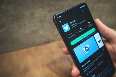 Twitter mobil uygulaması akıllı telefonda fotokopi uzayı ile birlikte. Google Play Store 'da sosyal medya uygulaması, karanlık tema. Krakow, Polonya - 11 Kasım 2022.