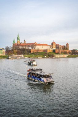 Wawel Kraliyet Kalesi manzarası ve Vistula Nehri gezi teknesi. Krakow, Polonya - 11 Kasım 2022.