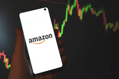 Amazon Inc. logosu telefon ekranında, hisse senedi çizelgesinde, çizgi grafik çubuğunun koyu arka planında sergileniyor. Swansea, İngiltere - 26 Ağustos 2021.