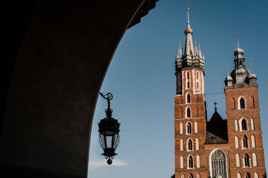Polonya 'nın eski Krakow kasabasındaki Pazar Meydanı' nda Aziz Marys Bazilikası. Kemerden fenerle bak.