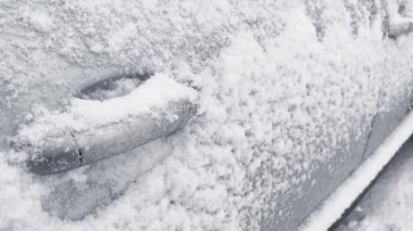 Car door handles covered in snow during heavy snowfall in Winter.