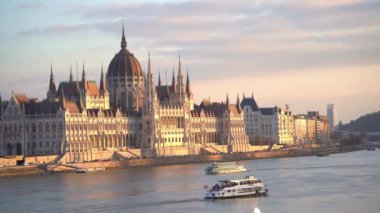Danube River Cruise boats. Hungarian parliament building at sunset. Budapest, Hungary - February 2, 2023.