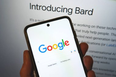 Google launches Bard AI. Google search bar on a phone in hand with release information on background. Google Bard AI vs OpenAI ChatGPT. Warsaw, Poland - February 8, 2023.