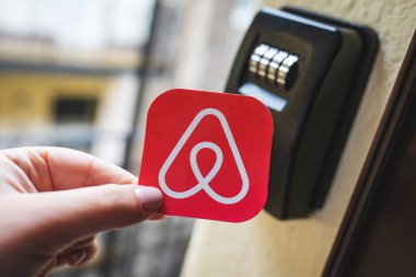 Akıllı bir anahtar kutusunun yanında Airbnb logosu var. Tatil evine habersiz giriş, turistler için kısa süreli konaklama rezervasyonları. Budapeşte, Macaristan - 3 Şubat 2023.