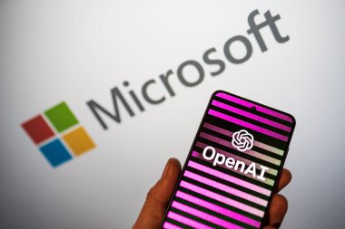 Bir elde telefonda OpenAI logosu ve arka planda Microsoft logosu bulanıklaştı. Bing, ChatGPT Al sohbet robotunu arama motoruna entegre ediyor. Varşova, Polonya - 15 Şubat 2023.