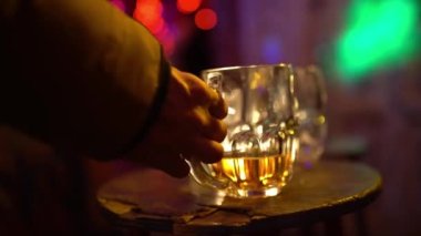 Man takes beer, drinks and puts the empty beer glass on the table in a bar. Dark night club background. Ruin pubs, nightlife concept.