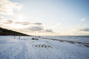 Kışın Baltık Denizi. Letonya, Jurmala yakınlarındaki karla kaplı plajda yürüyen insanlar.