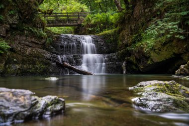 Sychryd Cascades veya Sgydau Sychryd Falls Dinas Rock, Pontneddfechan, Brecon Beacons Ulusal Parkı, Güney Galler, İngiltere yakınlarındaki Waterfall Country 'de ahşap köprü ile. Uzun pozlu su.