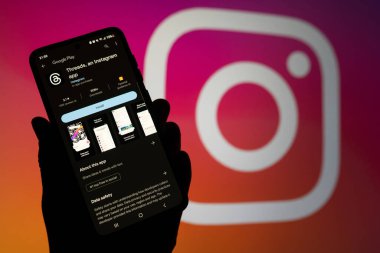 Google Play uygulamasında arka planda Instagram logosu olan bir telefon ekranı. Threads, Facebook Meta 'nın yeni bir sosyal medya, mikro blog platformu. Swansea, İngiltere - 10 Temmuz 2023