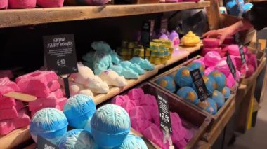 LUSH perakende mağazasından renkli el yapımı banyo bombaları alan bir kadın. Gösterişli güzellik ürünleri. Amsterdam, Hollanda - 23 Ekim 2023