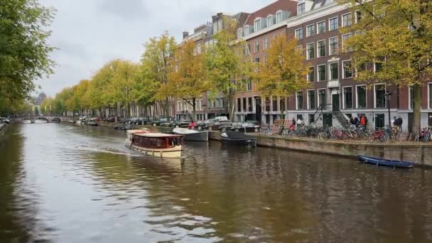 アムステルダム ケイザーズグレート運河 人々は秋のデイ運河クルーズのためのツアーボートで帆 公園自転車 オランダの伝統的な家屋 黄色い木 アムステルダム オランダ 10月 2023 — ストック動画