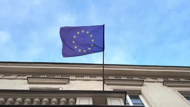 欧盟旗帜飘扬在一幢建筑物上 欧盟旗帜迎风飘扬 迎着蓝天飘扬 变焦效果 — 图库视频影像