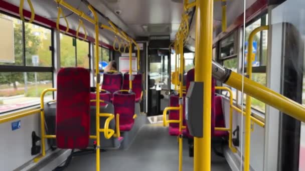 移動するZtm公共交通機関バスの内部 赤い座席の列 ドアの開いたボタンが付いている黄色いバス ハンドルの選択的な焦点 ワルシャワ ポーランド 10月 2023 — ストック動画