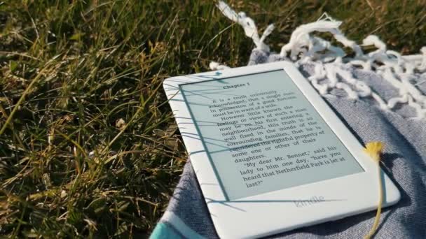 Vit Amazon Kindle Bok Läsare Picknick Filt Gräset Utomhus Park — Stockvideo