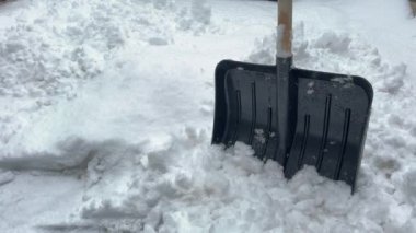 Kar yağışı sırasındaki siyah kar küreği. Elle kar temizleme, temizleme ya da kış bakım konsepti. Ağır çekimde düşen kar taneleri.