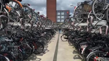 Bisiklet park yeri tesisi. Adam, Hollanda 'nın çift katlı bisiklet raflarının üst kısmını kullanıyor. Açık havada duran bisiklet sıraları. Nijmegen, Hollanda - 3 Temmuz 2024.