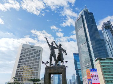 JAKARTA - Endonezya. 07 Kasım 2022: Mavi gökyüzünün altında yüksek binalar bulunan hoş geldin heykelinin alçak açılı görüntüsü. 4k çözünürlükte çizgi film
