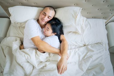 Romantik çiftin yatakta birlikte yatarken birbirini kucaklamasını tepeden aşağı izlemek. Evde vuruldu.