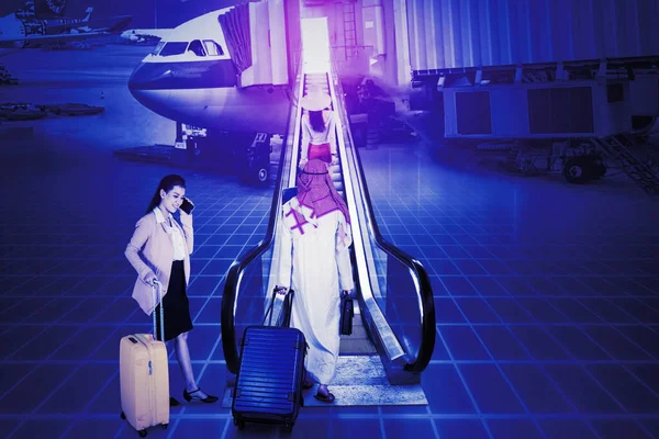 三个人背着行李在自动扶梯上走向有虚拟屏幕背景的飞机 — 图库照片