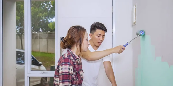 若いカップルは幸せそうに見えますが 新しい家の壁にローラーで絵を描く — ストック写真