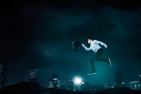 Hombre Empresario Llevando Maletín Mientras Salta Con Fondo Ciudad Noche —  Fotos de Stock