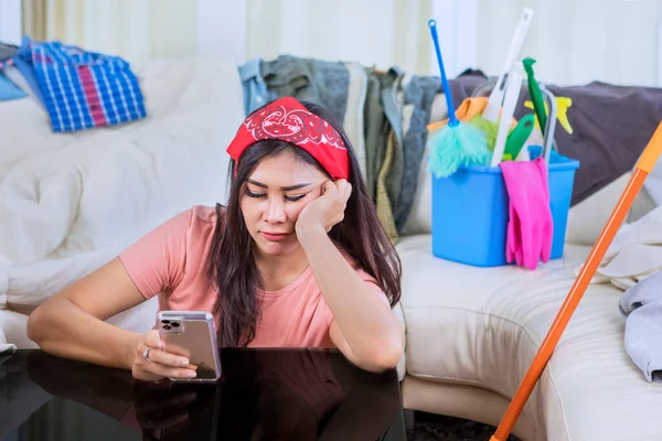 Blisko Domu Pokojówka Wygląda Znudzony Podczas Korzystania Telefonu Komórkowego Niechlujnym — Zdjęcie stockowe