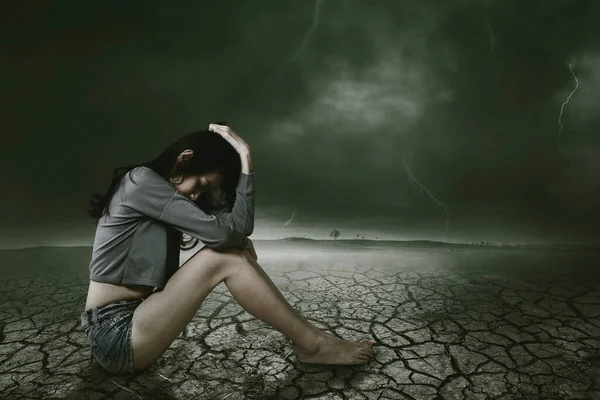 孤独的女人在裂开的土地上和雷鸣般的天空中背影 — 图库照片
