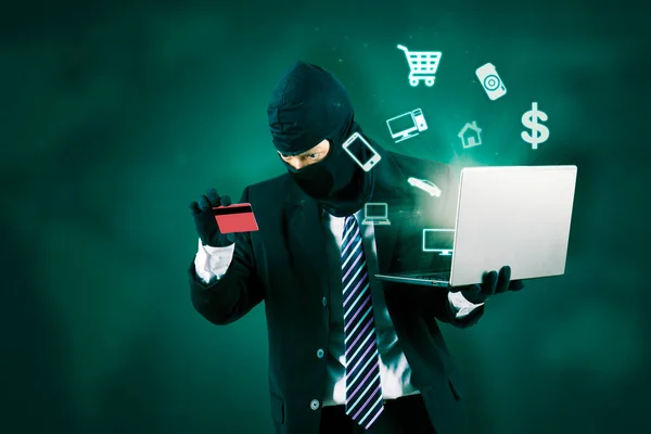 盗窃者 戴面具 手持笔记本电脑和信用卡的黑客 — 图库照片