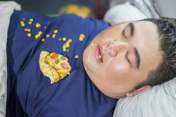 吃披萨和巧克力糖果的时候 超重的男人睡在屋里 — 图库照片