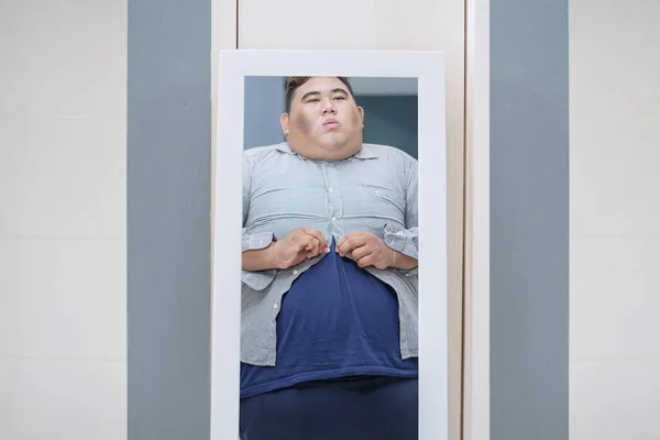 体重超标的年轻亚洲男子穿着紧身衣照镜子 — 图库照片