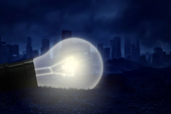 暗い都市の背景を持つ砂の上に照明された電球 ストック画像