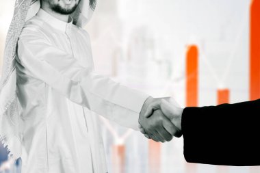 Arap işadamı ayakta dururken meslektaşıyla tokalaşıyor